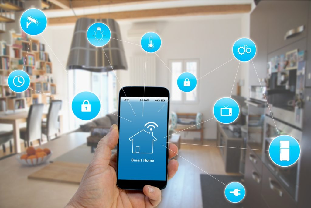 Hand holding smartphone with smart home application on screen