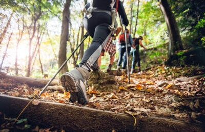 hiker woman with trekking sticks climbs steep on mountain trail